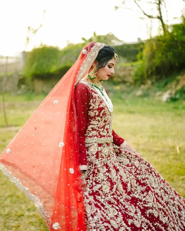Bride in a red lehenga with a flowing veil, photographed outdoors