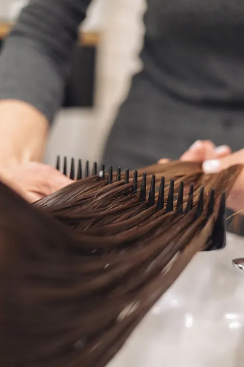 Stylist combing hair through a wet styling session