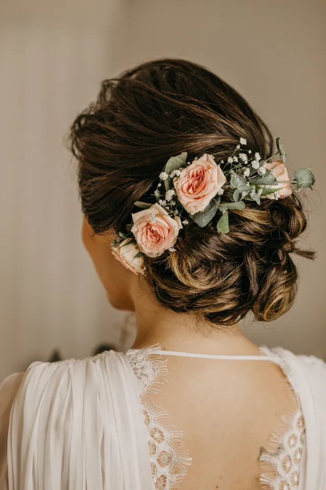 Bridal hair updo styled with pale pink roses and baby's breath